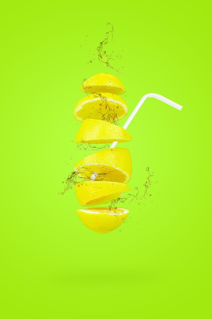 Summer refreshing drink. Levitation of lemon slices with a straw on light green background. Levitation of freshly cut lemon, vertical, closeup.
