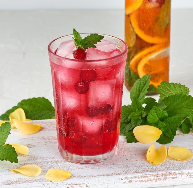 Summer refreshing drink with berries of cranberries and pieces of ice in a glass 