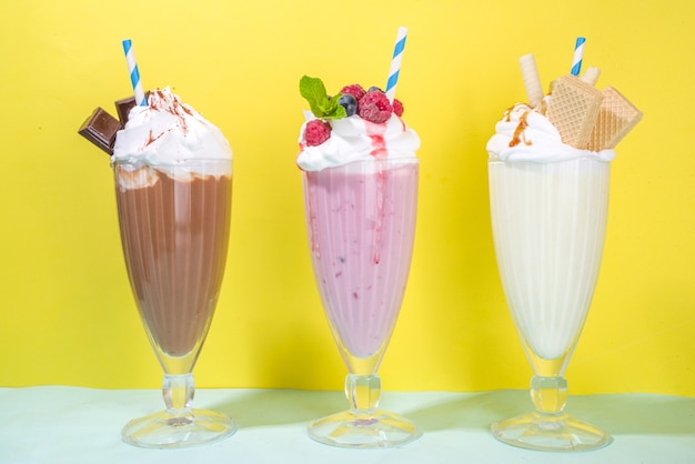 Summer refreshing drinks, milkshakes, crazy shakes with ice cream, berries, vanilla, chocolate. On a bright blue yellow background