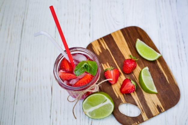 Summer refreshing strawberry drink in a glass with mint and lime