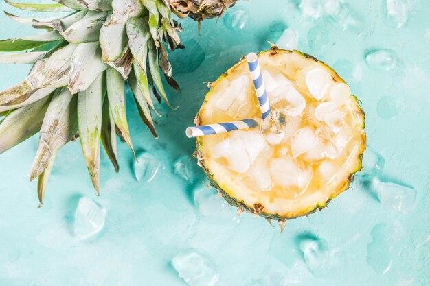 Summer refreshment drink concept tropical pineapple cocktail or juice in pineapple with ice