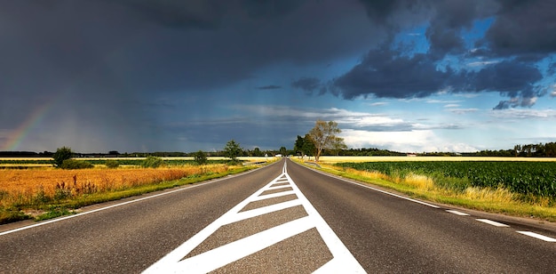 Summer road Stormy sky and rainbow Beautiful view Copy space