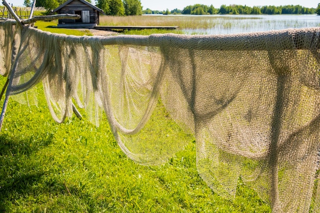 A summer rural landscape hanging drying fishing nets in the fresh air on the shore of the lake