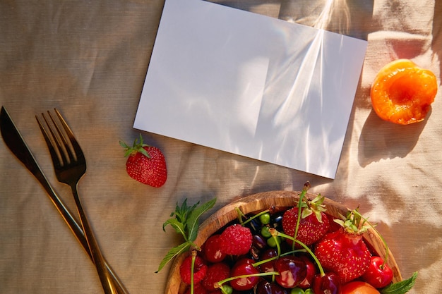 Summer rustic stationery card mock up among strawberries apricot cherry raspberry mint under hard shadows sunlight Top view copy space Menu or recipe design