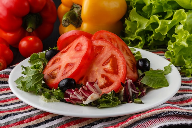 Summer salad with tomatoes in white plate on wood table