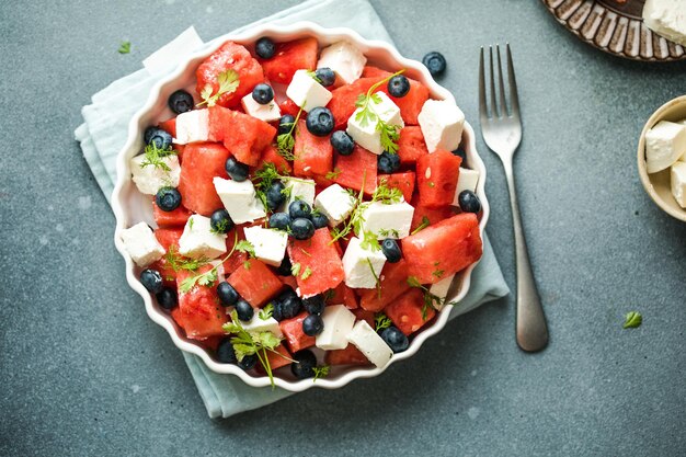 Summer salad with watermelon feta cheese and blueberry on a gray background Vegan European food