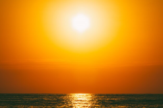 夕暮れ時のオレンジ色の空と夏の海の風景