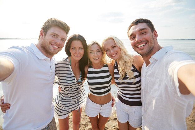 여름, 바다, 관광, 기술, 그리고 사람들의 개념 - 해변에서 카메라를 들고 셀카를 찍고 있는 웃고 있는 친구들