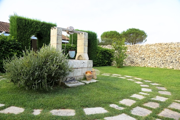 Summer season in Italy. Desing water well in an elegant garden.