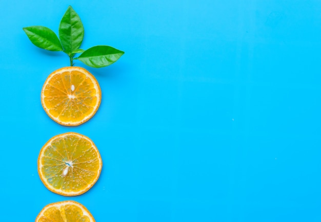 Foto estate della frutta arancio della fetta con le foglie verdi sull'azzurro