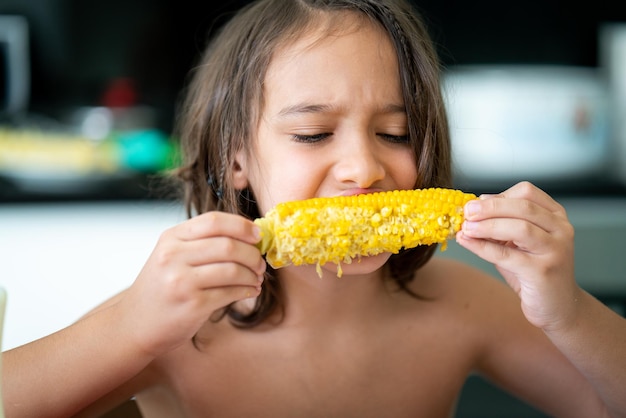 Summer snack, little boy sitting and eating corn High quality photo