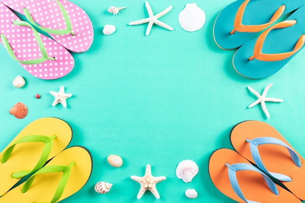Photo summer social distancing concept. four flip flops, starfish and seashell on green pastel background.