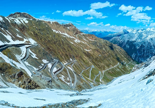 Вершина летнего перевала Стельвио с альпийской дорогой и снегом на склоне (Италия)