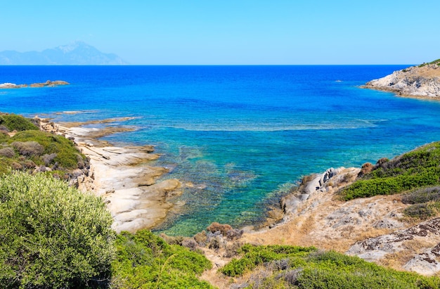 Ландшафт морского побережья лета каменистый с видом на гору Аттос в далекие (Халкидики, Ситония, Греция).