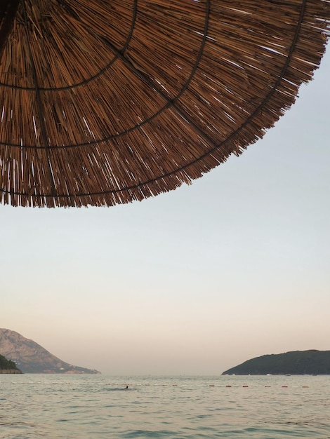 Summer straw beach umbrella in front of the sea