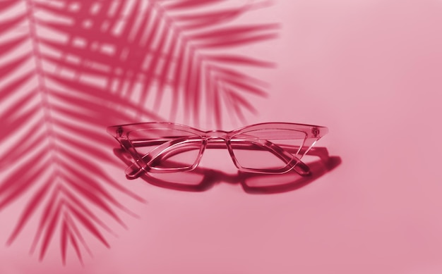 Summer sunglasses on a pink background. New 2023 trending PANTONE 18-1750 Viva Magenta colour