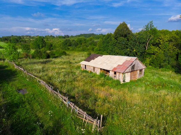 Summer. Sunny day. Abandoned old wooden farmhouse on a green meadow