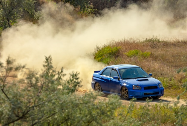 Giornata di sole estivo. pista sterrata per il rally. un'auto attraversa una curva e fa molta polvere 06