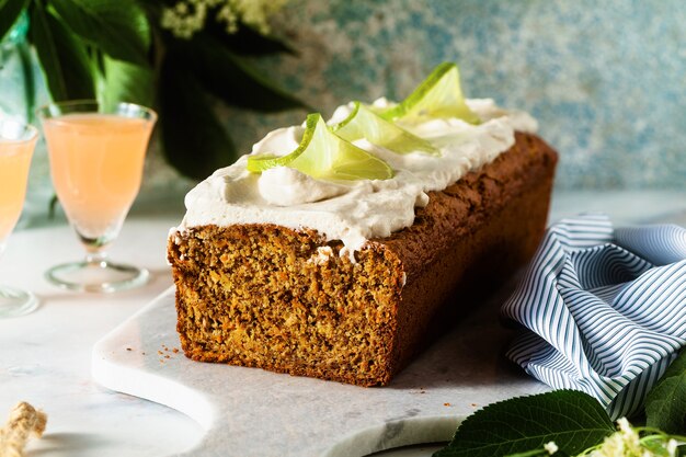 Summer sweet loaf cake on a table with flowers and a drink in glasses.