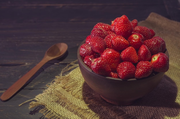 여름 과자 나무 숟가락이 달린 점토 그릇에 담긴 딸기