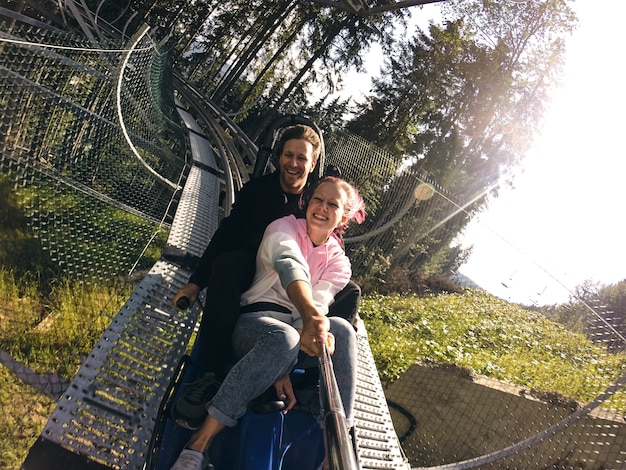 Summer toboggan run rodelbahn with many curves on a mountain. Alpine coaster in summer and autumn beautiful landscapes. Fast ride fun of young couple travelling.