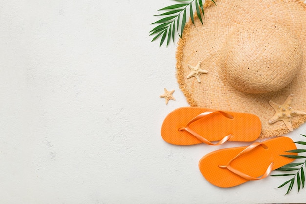 Summer travel concept Flip flops summer hat and starfish on white Top view on colored background