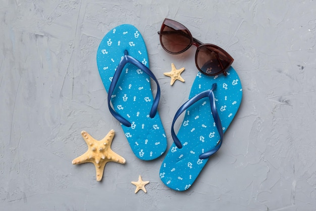 Summer travel concept Flip flops sunglasses and starfish on white Top view on colored background