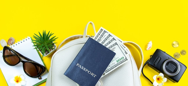 Summer travel concept Passport money sunglasses and a camera on a yellow background