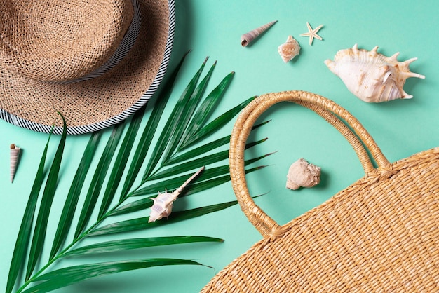 Summer travel concept with women straw bag hat palm leaves shells on trendy yellow and green background Top view Copy space