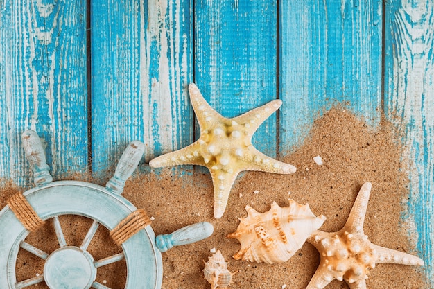 Summer travel vacation sailor's captain's wheel starfish and seashell on sand