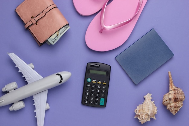 Summer. Traveler, beach accessories, toy airplane, calculator on purple.