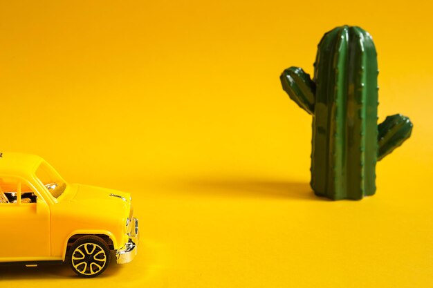 Summer trip by car-a yellow car on a background with a cactus-a tour to the desert, to the sea. Independent travel, domestic tourism. Taxi for a sightseeing tour. Copy space