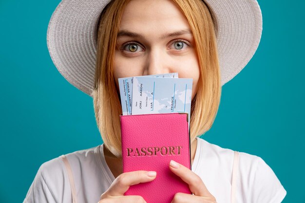 여름 여행 휴가 여행 티켓과 함께 외국 여권을 들고 흰색에 행복한 여자 파란색 여행사 비자 사무소에 고립 된 카메라를보고