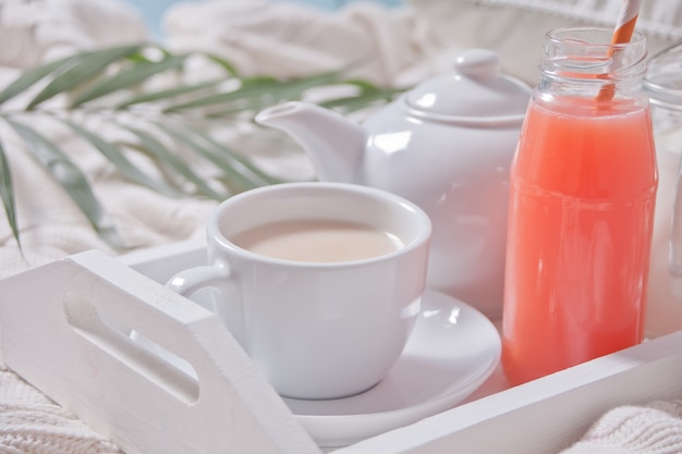 Summer tropical breakfast with cup of tea, teapot and refreshing exotic juice