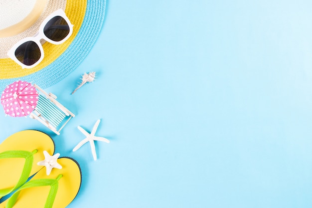 Summer or vacation. Beach hat, sunglasses, sunbed, flip flops on light blue background. Copy space.