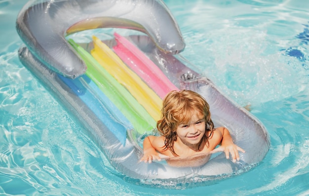 Summer vacation. Child in swimming pool. Summertime. Smiling boy on inflatable rubber mattress.