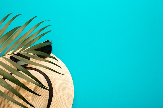 Summer vacation concept. Men's hat, sunglasses and palm branch on a bright background