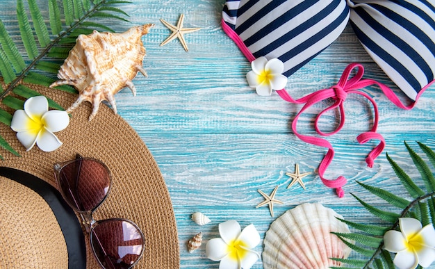 夏休みのコンセプト。青い木製の背景に貝殻とヒトデと麦わら帽子とビーチアクセサリー