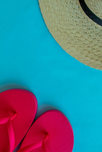 Summer vacation hat and flip flops on a blue background vertical background