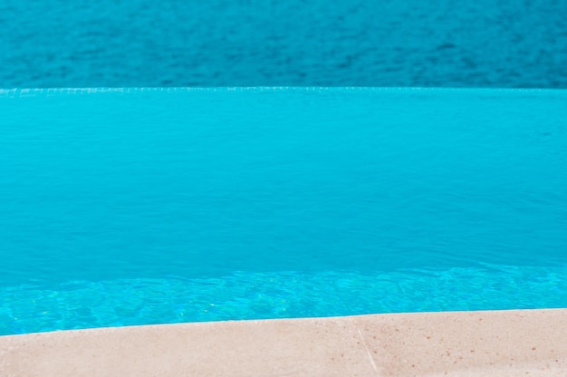 Summer vacation at poolside. Infinity swimming pool with sea on bright summer day