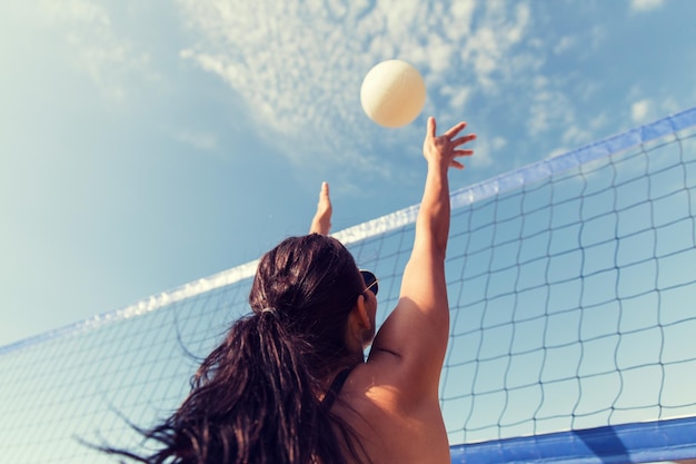 여름 휴가, 스포츠, 레저 및 사람들의 개념 - 해변에서 배구를 하고 공을 잡는 젊은 여성