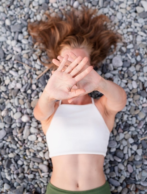 Photo summer vacation top view of young smiling woman in swimsuit lying on stone beach covering face