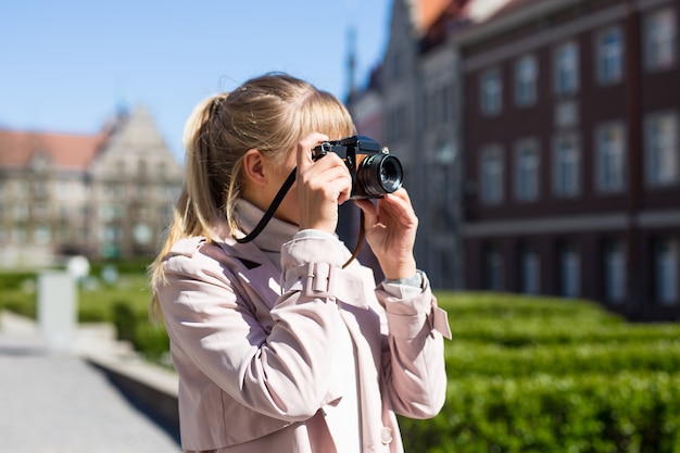 Summer vacation and travel concept - female tourist taking photos of old town