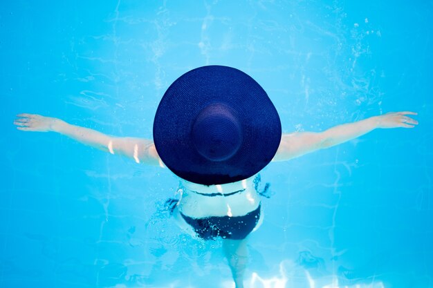 여름 휴가 및 여행 개념 - 모자를 쓴 날씬한 여성이 수영장이나 바다에서 수영하는 모습