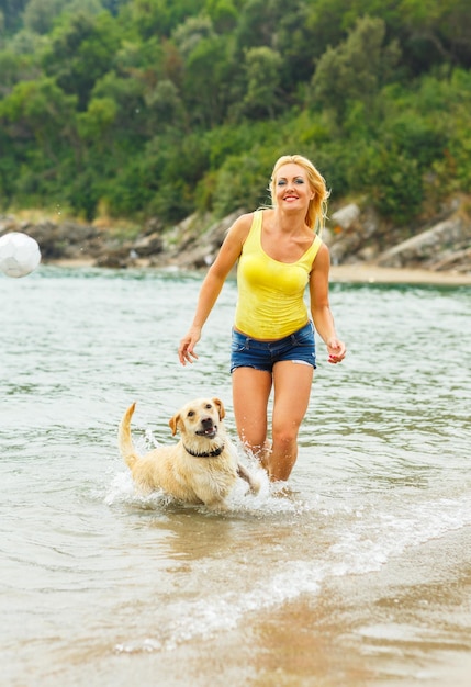 Foto donna in vacanza estiva con il cane che gioca sulla spiaggia