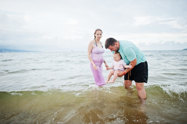 Фото Летние каникулы. родители и люди на свежем воздухе с детьми. счастливых семейных праздников. отец, беременная мать, дочка на морском песчаном пляже.