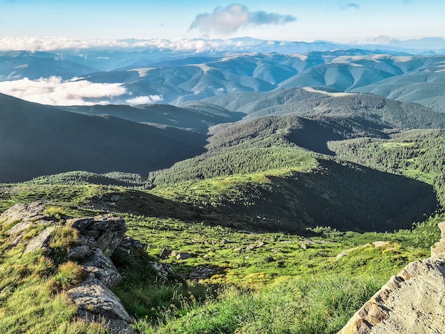 Vista estiva dal picco di montagna al cielo blu con nuvole sotto