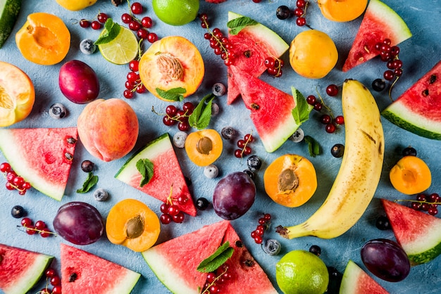 写真 夏のビタミン食品の概念、さまざまなフルーツとベリースイカピーチミントプラムアプリコットブルーベリースグリ、創造的なフラットは明るい青の背景に横たわっていた
