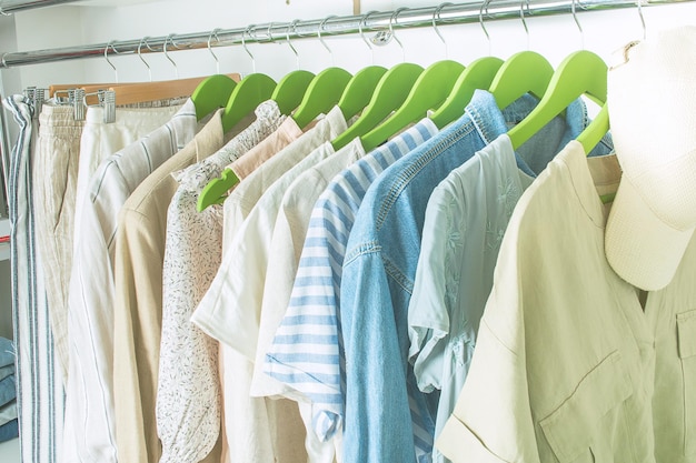 Summer wardrobe with linnen clothes on green hangers