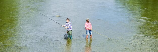 Fine settimana estivo pescatore felice con canna e rete hobby e attività sportiva pescare insieme uomini in acqua la pesca è molto più che pesce amicizia maschile pesca padre e figlio